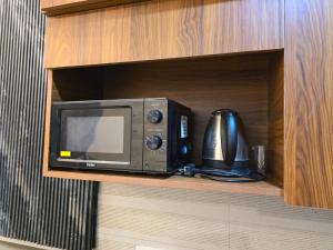 a microwave sitting on a shelf in a cabinet at Siri Stays in Greater Noida