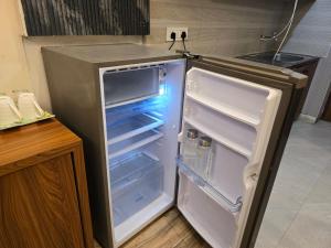 an empty refrigerator with its door open in a kitchen at Siri Stays in Greater Noida