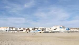 a group of people on a beach with buildings at Casa 3 min andando playa AC WiFi 8 pax Doñana in Matalascañas