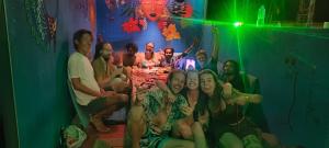 a group of people sitting around a table in a room at Funky Art Beach House in Alleppey