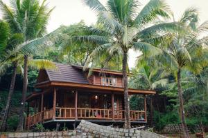 a house with palm trees in front of it at Tre Vibe Resort Daklak in Buôn Jung