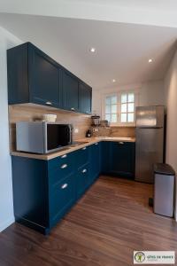 a kitchen with blue cabinets and a stainless steel refrigerator at gîte dans maison bourgeoise in Millau
