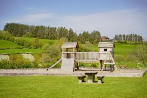 a small playground with a play house in a field at Daisy in Rhayader