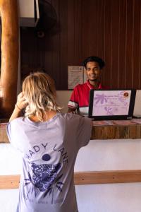 a woman standing in front of a counter with a laptop at Hangten's Surf Skate Hostel in Arugam Bay