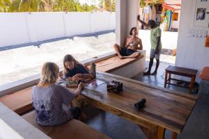 a group of people sitting around a wooden table at Hangten's Surf Skate Hostel in Arugam Bay