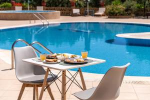 a table with food on it next to a swimming pool at Joanna's Stone Villas in Vasilikos