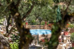 a swimming pool in a garden with an umbrella at Joanna's Stone Villas in Vasilikos