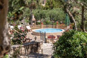 a swimming pool in a garden with flowers and trees at Joanna's Stone Villas in Vasilikos