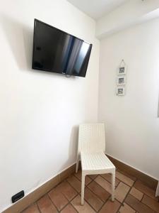 a room with a chair and a flat screen tv on the wall at Lighthouse Taranto in Taranto