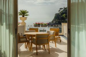 a table and chairs on a balcony with a view of the ocean at Mazzarò Sea Palace - The Leading Hotels of the World in Taormina