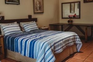 a bedroom with a bed with a blue and white striped blanket at Charming Self Catering Apartment in Phalaborwa +25 photos