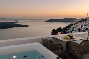 a bath tub with a table and chairs and the ocean at Agave Santorini Design Boutique Hotel in Imerovigli