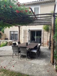 a wooden table and chairs under a wooden pergola at Le pavillon in Aubignan