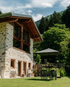 a building with a table and an umbrella in the grass at Chalet Noèr in Ledro
