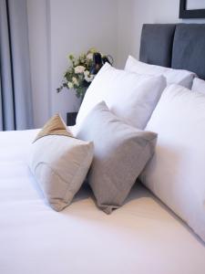 a bed with white pillows and a vase of flowers at Divina Tower Apart Hotel in Asunción