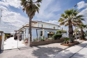 a house with palm trees in front of it at Bagno Lunezia in Marina di Carrara