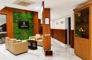 a lobby with chairs and a green wall at Hotel Sakthi in Kottayam