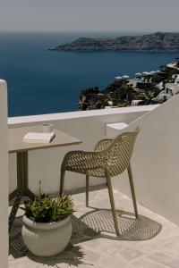 a chair and table on a balcony with a view of the ocean at Agave Santorini Design Boutique Hotel in Imerovigli