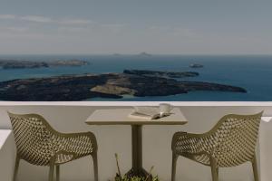 a table and chairs with a view of the ocean at Agave Santorini Design Boutique Hotel in Imerovigli