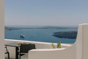 a balcony with a table and a boat in the water at Agave Santorini Design Boutique Hotel in Imerovigli +33 photos