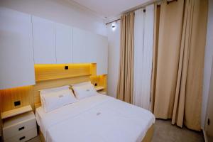 a bedroom with a white bed and a window at The Moon Apartment in Kigali