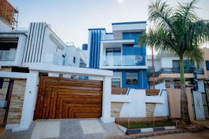 a house with a wooden garage door and palm trees at The Moon Apartment in Kigali
