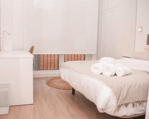 una camera da letto bianca con un letto su cui sono appoggiati gli asciugamani di NIDOM experience a Madrid