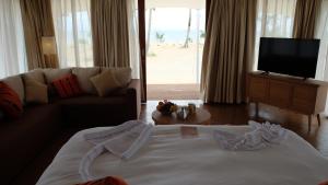 a living room with a couch and a tv and a bed at Marahai Villa Morotai in Dehegila