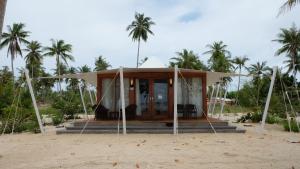 a small house on the beach with palm trees at Marahai Villa Morotai in Dehegila