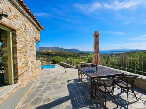 a patio with a table and an umbrella at Villa Rokanes Glass Stone with Pool in Kouvéllai