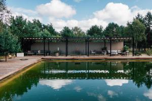 a pavilion with a pond in front of it at Amalia Glamp in Wierzchosław