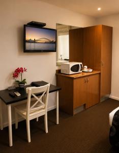 a room with a kitchen with a table and a microwave at Belmercer Motel in Geelong