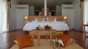 a bedroom with a bed and a table with a bowl of fruit at Marahai Villa Morotai in Dehegila