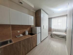 a kitchen with white cabinets and a bed in a room at GUM University Apartment in Ulaanbaatar