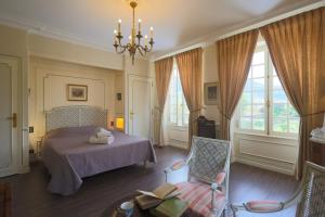 a bedroom with a bed and a chair and windows at Chambres d hôtes dans maison bourgeoise Douce France in Millau +52 photos