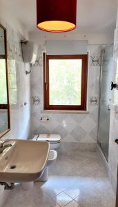 a bathroom with a sink and a toilet and a window at Laurus Home Restaurant B&B Cilento in Trentinara