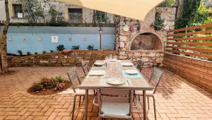 a table and chairs in a patio with a stone wall at Laurus Home Restaurant B&B Cilento in Trentinara