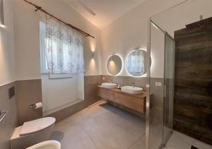 a bathroom with two sinks and a glass shower at Isuleddu Room & Stairs in La Maddalena