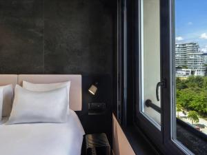 a bed with white pillows in a room with a window at TRIBE Paris Batignolles in Paris