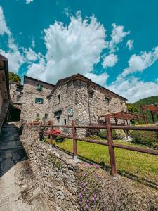 an old stone building with a wooden fence at Agriturismo Casa Turchetti -Nature & Pool & Relax tra Lunigiana, Nord Toscana e Cinque Terre in Comano