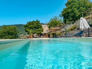 a swimming pool with chairs and an umbrella at Agriturismo Casa Turchetti -Nature & Pool & Relax tra Lunigiana, Nord Toscana e Cinque Terre in Comano