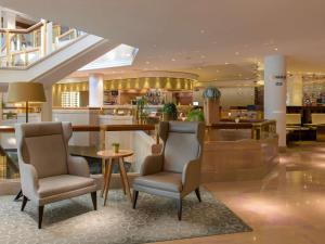 a hotel lobby with two chairs and a bar at Mövenpick Hotel Geneva in Geneva