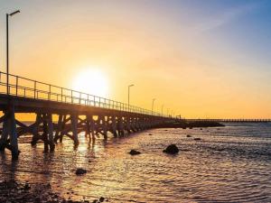 a pier with the sun rising over the water at Moonta Bay Hideaway in Port Moonta