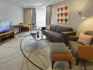 a living room with a couch and a television at Mövenpick Hotel Münster am Aasee in Münster
