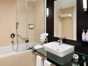 a bathroom with a sink and a shower at Mövenpick Hotel Jumeirah Lakes Towers Dubai in Dubai