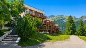 a building on top of a hill with mountains in the background at Hostdomus - Lumiere Apartment R15 in San Sicario