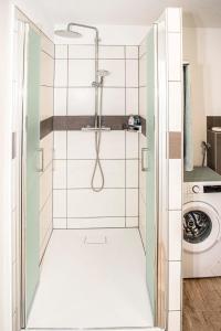 a shower in a bathroom with a washing machine at FeWo Seidenglanz in Dillenburg +64 photos