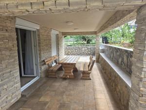 a porch with a wooden bench on a stone wall at Apartment Tulipan in Klimno
