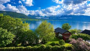 a house on the shore of a lake with mountains at Charming Casa Hauge BB Sunset Room in Sandane