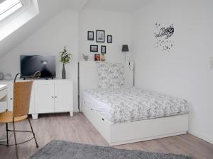 a white bedroom with a bed and a desk at FeWo Seidenglanz in Dillenburg